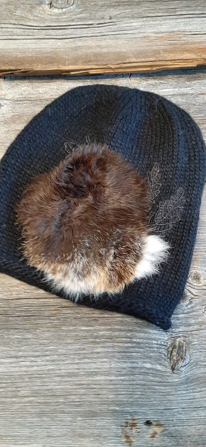 Melna cepure ar skaistu dabīgo kažokādu. Vienā eksemplārā.  Mīksta, silta, stilīga adīta rokām no kvalitatīvas alpakas un merīno dzijas. 
