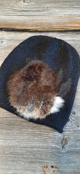 Melna cepure ar skaistu dabīgo kažokādu. Vienā eksemplārā.  Mīksta, silta, stilīga adīta rokām no kvalitatīvas alpakas un merīno dzijas.